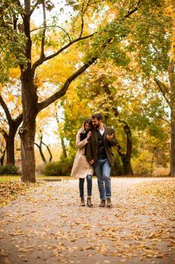 Güz parkında yürüyen yakışıklı genç çift.