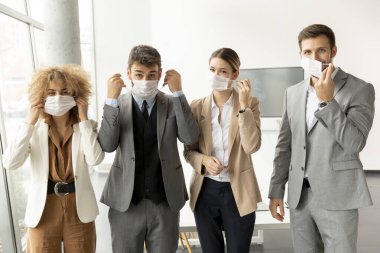 Genç iş adamlarının portresi ofiste koruyucu maskelerini çıkarıyor.