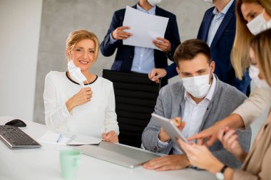 İş adamlarından oluşan bir ekip, ofiste virüs koruması olarak yüz maskeleri üzerinde çalışıyor.