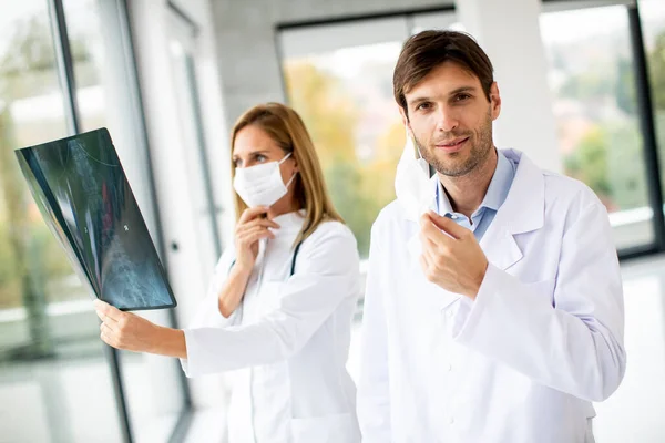 Equipe Médicos Examinando Xray Enquanto Médico Masculino Tirando Sua Máscara — Fotografia de Stock