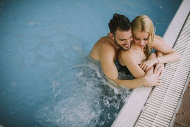 İç yüzme havuzunun havuz kenarında dinlenen sevimli genç çift.