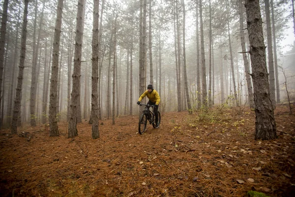 Handsome young man biking through autumn forest