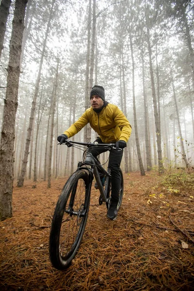 Handsome young man biking through autumn forest