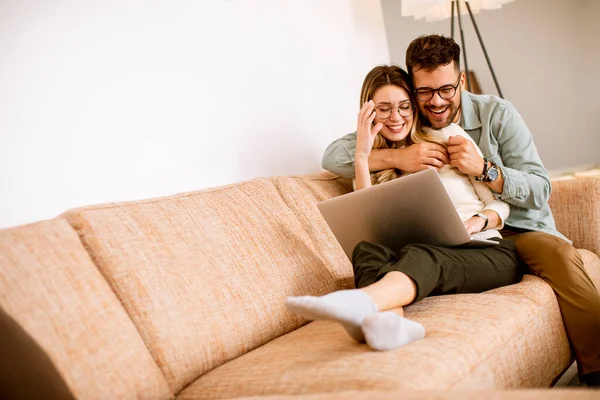 Bonito Jovem Casal Usando Laptop Juntos Enquanto Sentado Sofá Casa — Fotografia de Stock