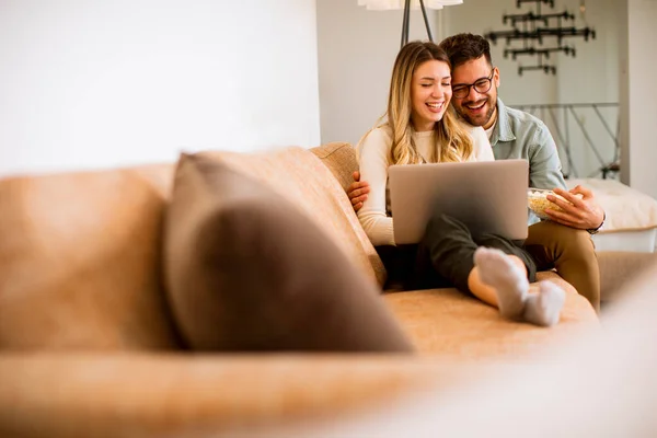 Bonito Jovem Casal Usando Laptop Juntos Enquanto Sentado Sofá Casa — Fotografia de Stock