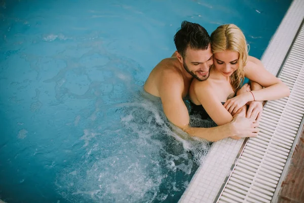 美しい若いカップルは 屋内スイミングプールのプールサイドでリラックス — ストック写真