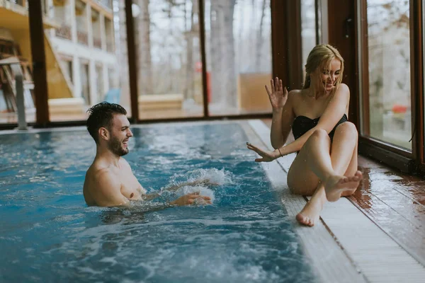美しい若いカップルは 屋内スイミングプールのプールサイドでリラックス — ストック写真