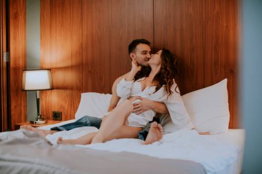 Odadaki yatakta birbirini seven ve kucaklayan çift.