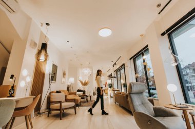 Modern oturma odasında yürüyen cesur genç bir kadın.