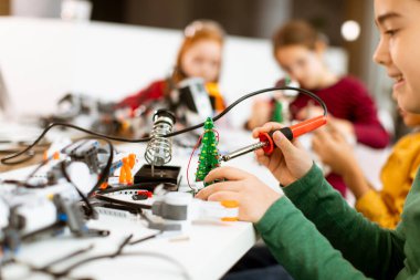 Robot sınıfında elektrikli oyuncak ve robot programlayan bir grup mutlu çocuk.