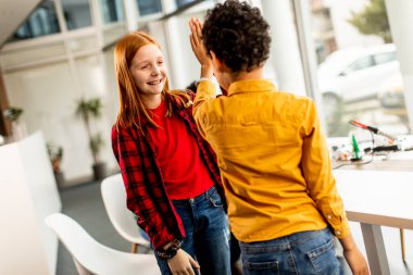 Robot sınıfında elektrikli oyuncakları ve robotları programlayan bir grup çocuğun önünde duran sevimli küçük arkadaşlar.