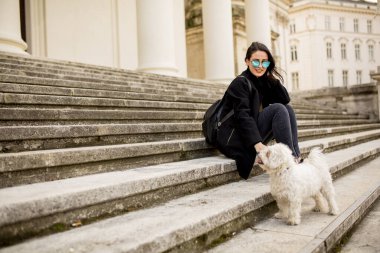 Avusturya, Viyana 'da yürüdükten sonra evcil köpeğiyle merdivenlerde oturan güzel kız.