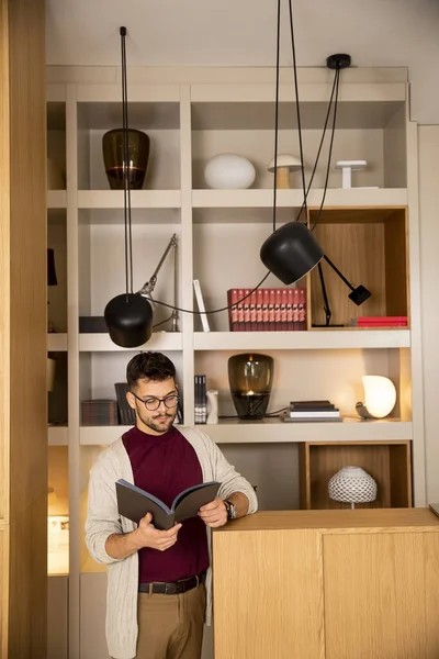 Jovem Bonito Roupas Casuais Com Óculos Lendo Livro Casa — Fotografia de Stock