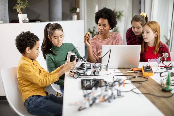 Grupa Szczęśliwych Dzieci Swoją Afroamerykańską Nauczycielką Fizyki Laptopem Programującą Zabawki — Zdjęcie stockowe