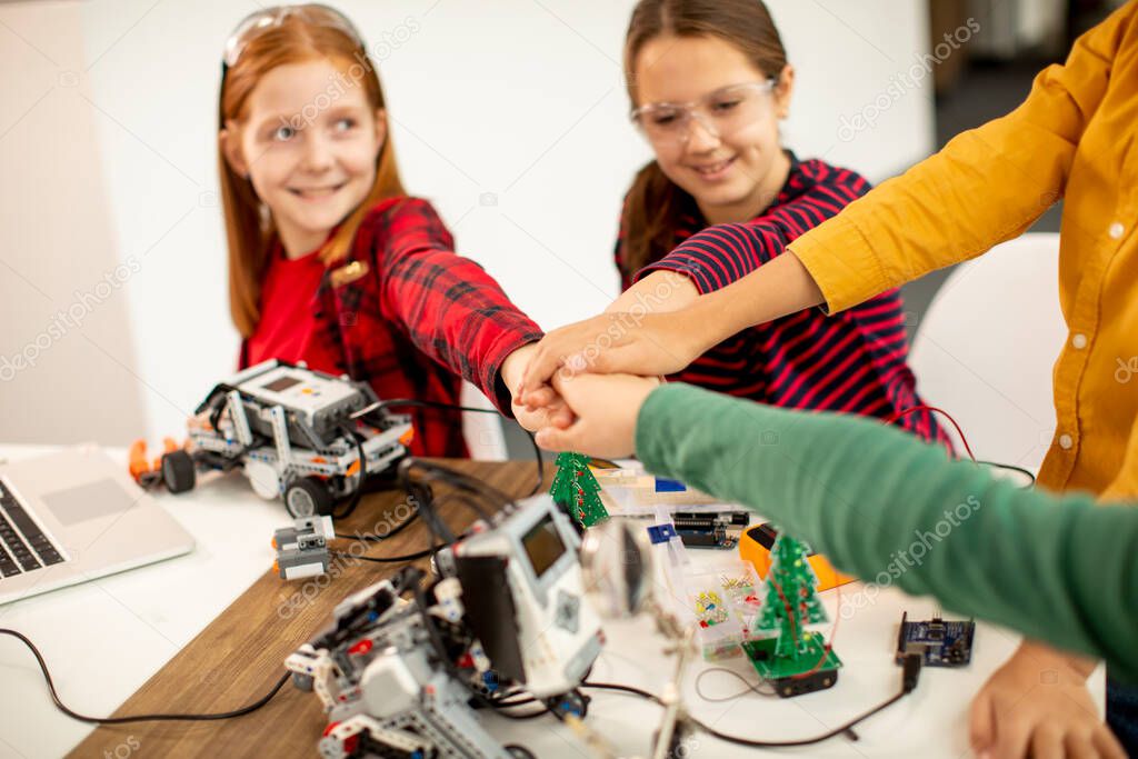 Group of happy kids programming electric toys and robots at robotics classroom