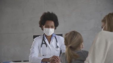 Anne ve küçük kızı Afrikalı Amerikalı kadın doktor tarafından pediatri muayenesinde.