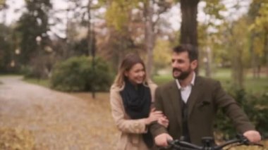 Sonbahar parkında elektrikli bisikletleri olan yakışıklı bir çift.