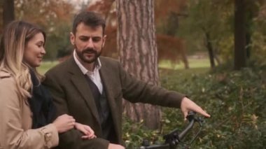 Sonbahar parkında elektrikli bisikletleri olan yakışıklı bir çift.