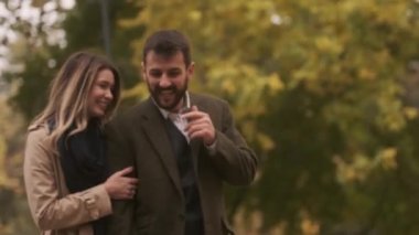 Güz parkında yürüyen yakışıklı genç çift.