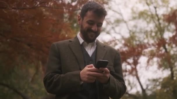 Knappe Jongeman Met Mobiele Telefoon Het Herfstpark — Stockvideo