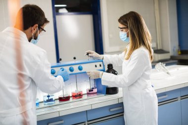 Genç araştırmacılar laboratuardaki flocculator 'daki kimyasal verileri analiz ediyorlar.