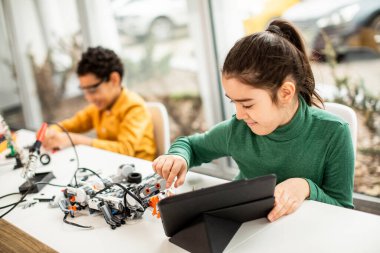 Robot sınıfında elektrikli oyuncak ve robot programlayan bir grup mutlu çocuk.