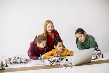 Robot sınıfında elektrikli oyuncak ve robot programlayan bir grup mutlu çocuk.