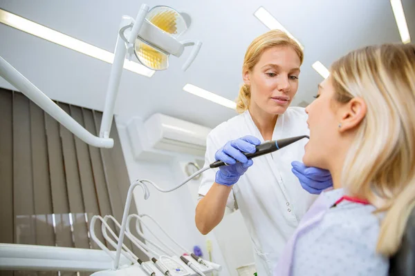 歯科クリニックで女性患者の歯をチェックする制服の医者 — ストック写真