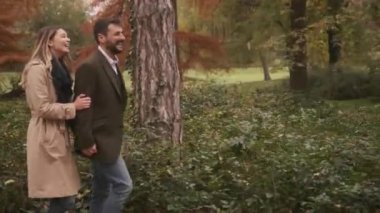 Güz parkında yürüyen yakışıklı genç çift.