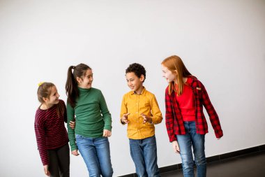 Kot pantolonlu, gülümseyen, beyaz duvarda yürüyen şirin çocukların portresi.