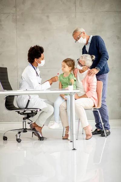 Senior couple with cute grandaughter black female doctor in the office