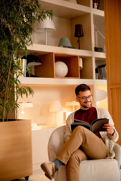 Jovem Bonito Roupas Casuais Com Óculos Lendo Livro Casa — Fotografia de Stock