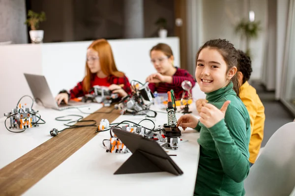 Group of happy kids programming electric toys and robots at robotics classroom