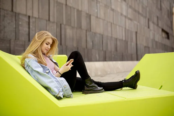 Young woman sitting in the city and use a mobile phone. Urban concept.