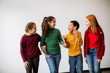 Kot pantolonlu, gülümseyen, beyaz duvarda yürüyen şirin çocukların portresi.