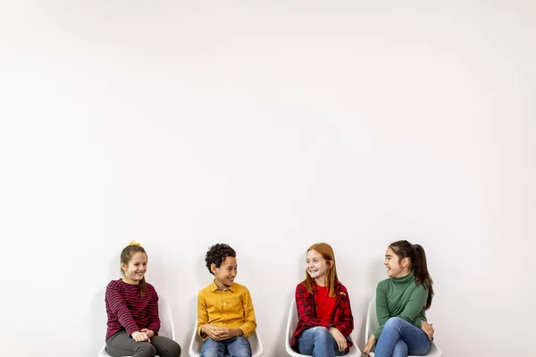 Portret Uroczych Małych Dzieci Dżinsach Siedzących Krzesłach Pod Białą Ścianą — Zdjęcie stockowe
