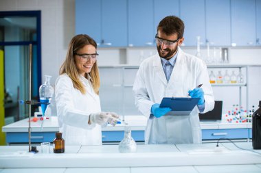 Genç araştırmacılar bir kimya laboratuvarının masasında dumanla deney yapıyorlar.