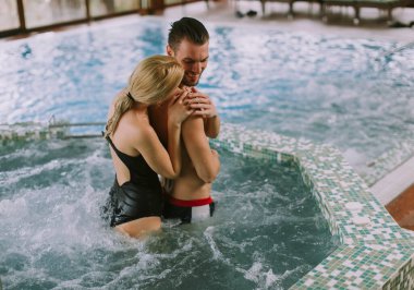 İç yüzme havuzunun havuz kenarında dinlenen sevimli genç çift.