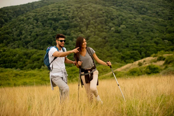 笑顔若いカップル歩くとバックパックで緑の丘の上 — ストック写真