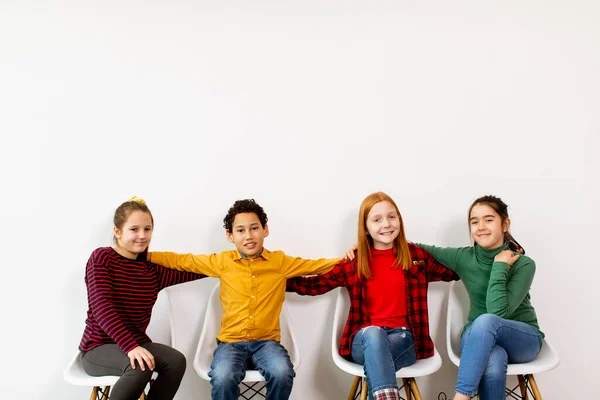 Portret Uroczych Małych Dzieci Dżinsach Siedzących Krzesłach Pod Białą Ścianą — Zdjęcie stockowe