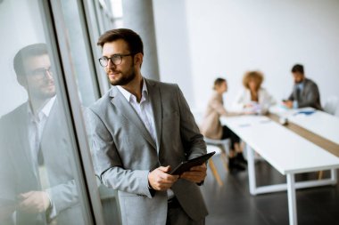 Ofiste dijital tablet kullanan yakışıklı genç iş adamı.