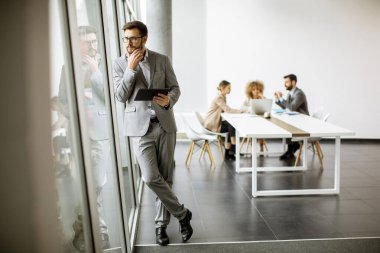 Ofiste dijital tablet kullanan yakışıklı genç iş adamı.