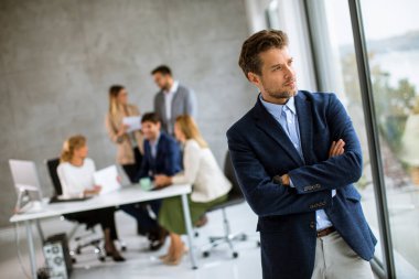 Yakışıklı genç iş adamı ekibinin önünde kendinden emin duruyor.