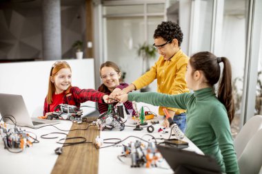 Robot sınıfında elektrikli oyuncak ve robot programlayan bir grup mutlu çocuk.