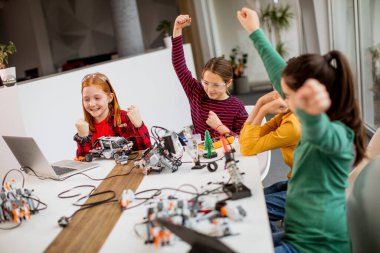 Robot sınıfında elektrikli oyuncak ve robot programlayan bir grup mutlu çocuk.