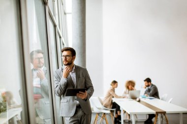 Ofiste dijital tablet kullanan yakışıklı genç iş adamı.
