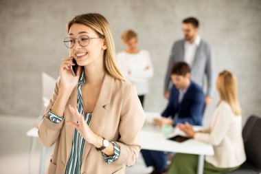 Ofiste duran genç ve güzel bir iş kadını takımının önünde cep telefonuna dava açıyor.