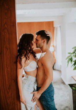 Genç çift apartmanın odasında sarılıp öpüşüyor.