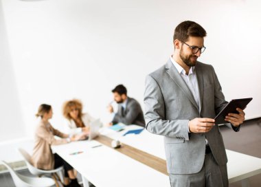 Ofiste dijital tablet kullanan yakışıklı genç iş adamı.