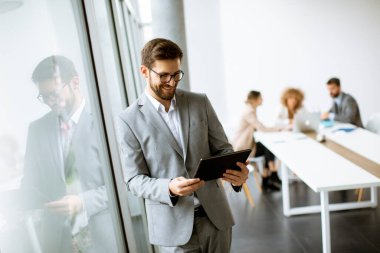 Ofiste dijital tablet kullanan yakışıklı genç iş adamı.